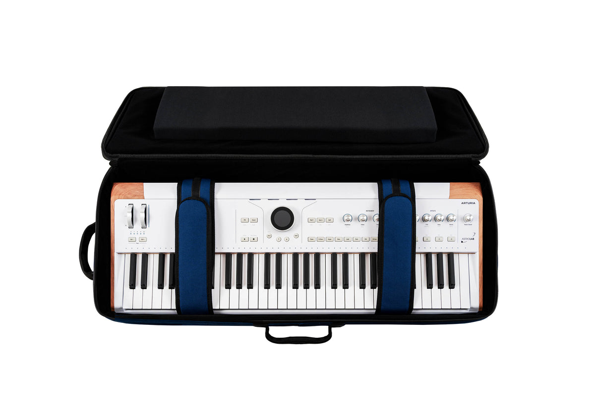 Open black Arturia soft case with blue padded straps holding a white 49-key keyboard with wood-panel sides.