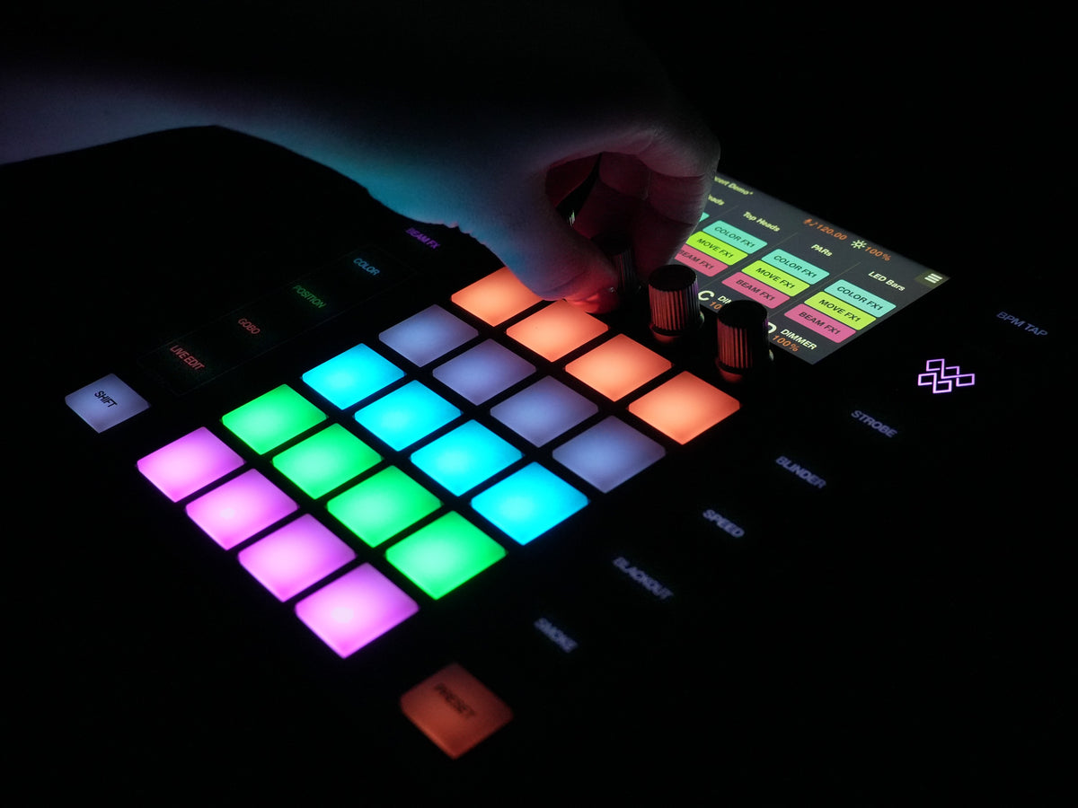 Hand turning an encoder on the Wolfmix W1 MK3 in a dark room, pads lit in color - Hollywood DJ
